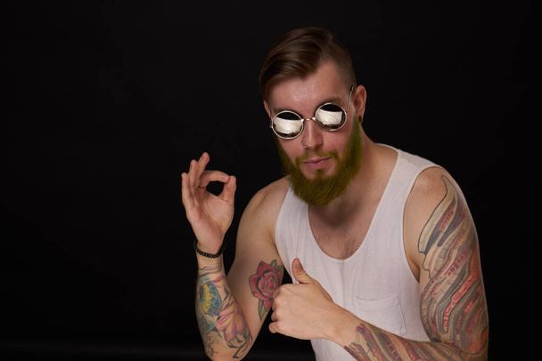 handsome man with tattoos on his arms fashion sunglasses dark background - Photo, Image