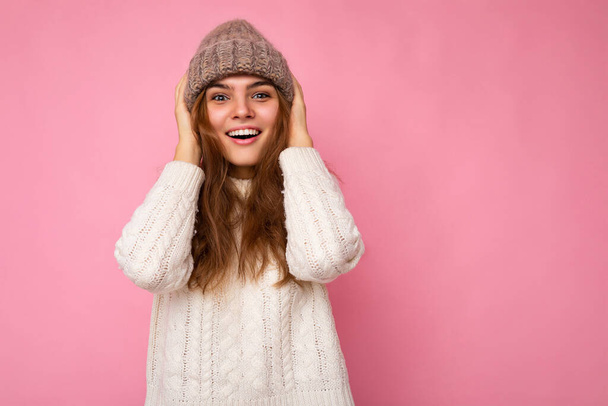Atraktivní úsměv šťastný mladý brunet žena stojící izolované přes barevné pozadí zdi na sobě každodenní stylový outfit ukazující emoce obličeje při pohledu do kamery - Fotografie, Obrázek