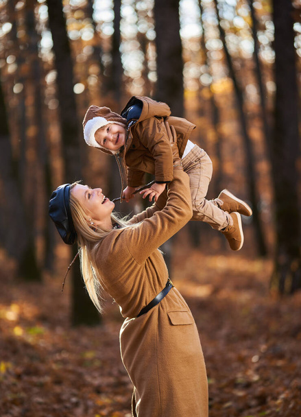 Young mother and her toddler son having a nice time in the forest, autumn time - Fotoğraf, Görsel