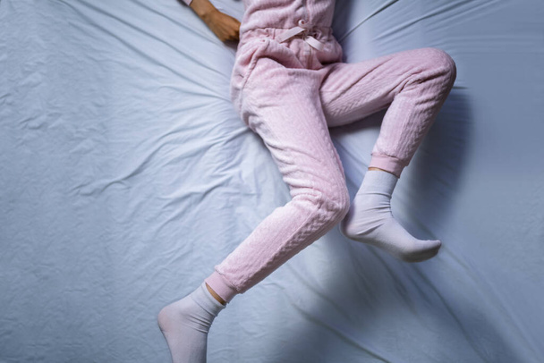 Αφροαμερικανή με σύνδρομο ανήσυχων ποδιών. Κοιμάσαι στο κρεβάτι - Φωτογραφία, εικόνα