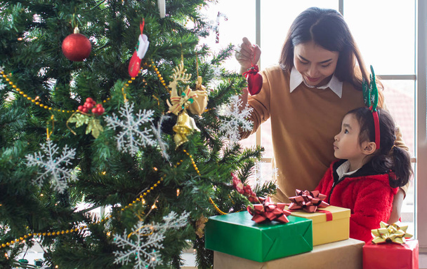 Ázsiai család, anya és gyermek lánya díszítő karácsonyfa úgy érzi, boldog és szórakoztató. A koncepció családi tevékenység decembertől januárig boldog karácsonyt és boldog új évet. - Fotó, kép