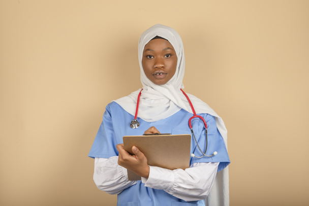Joven de religión musulmana sosteniendo portapapeles y escribiendo algo de cerca. Atención médica, seguro, prescripción médica. - Foto, Imagen