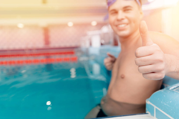 Young man swimmer showing okay thumb sign in pool, swimming competition concept - 写真・画像