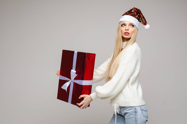 Noel Baba şapkalı güzel bir kadın hediye kutusuyla poz veriyor. - Fotoğraf, Görsel