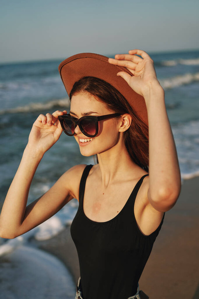 veselá žena v slunečních brýlích a klobouk u oceánu procházka léto - Fotografie, Obrázek