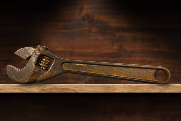 Fechar-se de uma velha chave ajustável enferrujada em uma prateleira de madeira. Século XIX, Itália. - Foto, Imagem