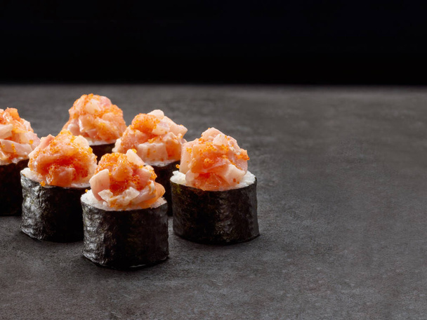 Rolo de sushi japonês Maki. Pedaços de prato asiático com salmão e peixe de rocha em cima no fundo de concreto escuro. Copiar imagem espacial. Um único objecto. De dentro para fora sushi - Foto, Imagem