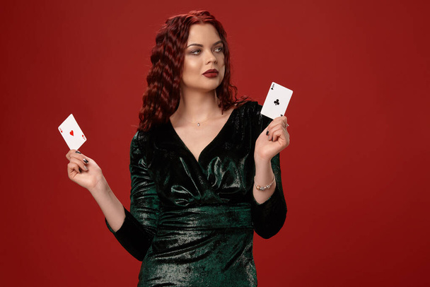 Mujer sexy joven con un pelo rizado rojo sosteniendo ases, sobre un fondo rojo. Poker
 - Foto, imagen