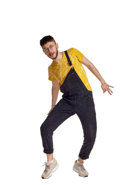 Full-length portrait of a funny guy dancing in studio isolated on white background. - Foto, afbeelding