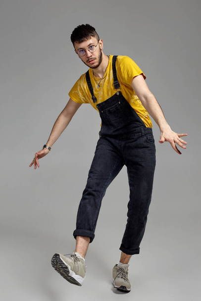 Full-length portrait of a funny guy dancing in studio on a gray background. - Foto, Bild