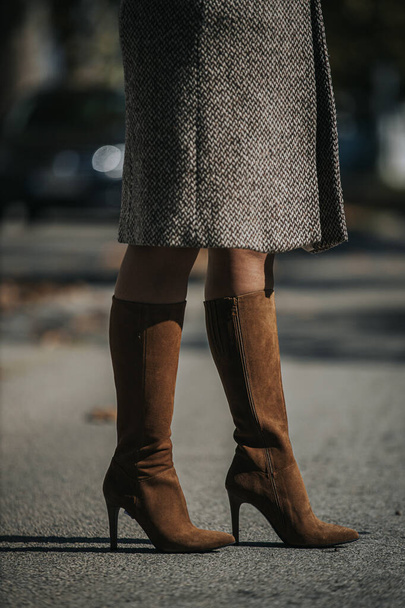 Un colpo verticale di donna che indossa stivali alla moda marrone camoscio ginocchio-alto all'aperto - Foto, immagini