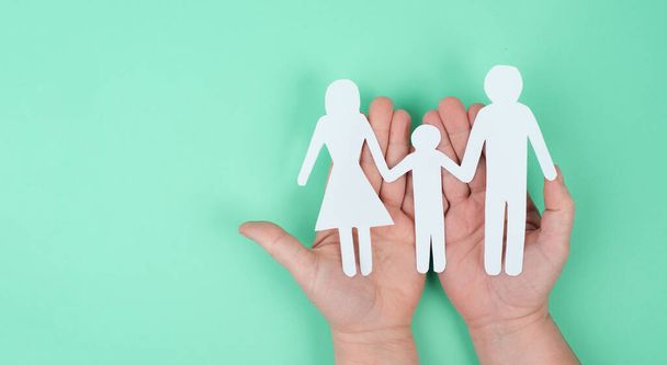 Parents with one child holding hands, paper cut out, copy space, green colored background, relationship - Valokuva, kuva