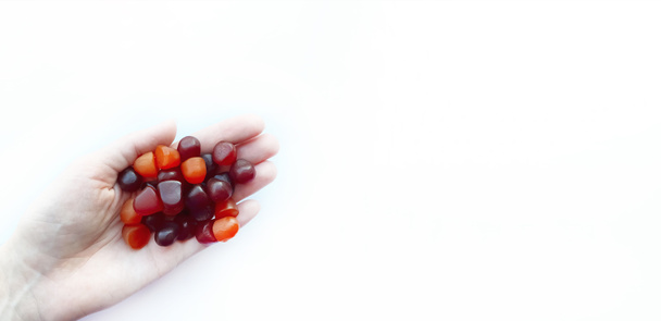 Skupina červené, oranžové a fialové multivitamínové gumy v ruce izolované na bílém pozadí - Fotografie, Obrázek