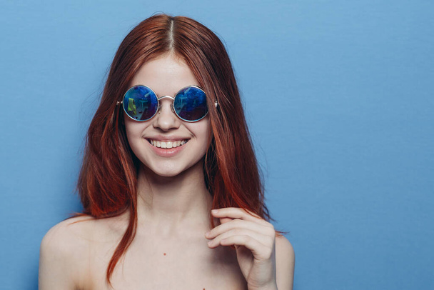vivace donna dai capelli rossi in occhiali blu spalle nude in posa - Foto, immagini
