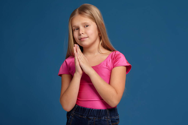 Porträt eines entzückenden emotionalen kleinen Mädchens auf blauem Hintergrund - Foto, Bild