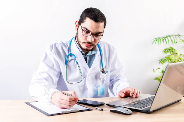 A white Caucasian doctor working at his clinic desk - Photo, image