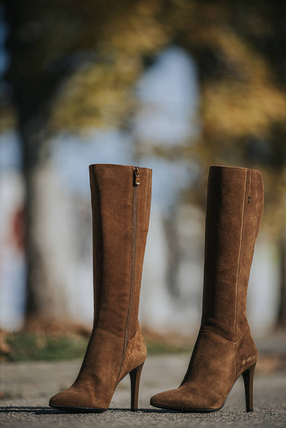 A vertical shot of fashionable brown suede knee-high boots outdoors - Foto, afbeelding