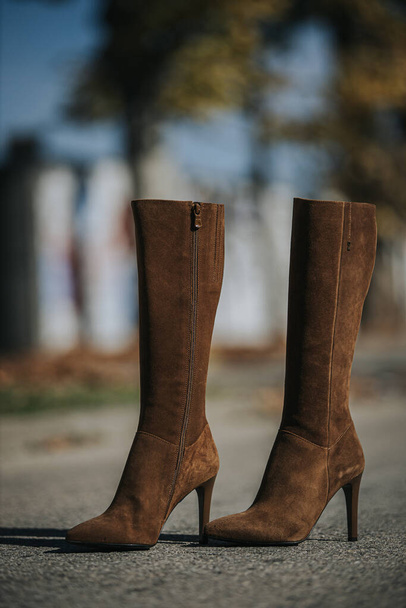 A vertical shot of fashionable brown suede knee-high boots outdoors - Foto, immagini