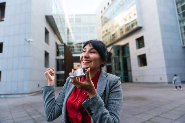 Mujer latina de negocios enviando mensajes de voz en su teléfono móvil en la calle. - Foto, Imagen