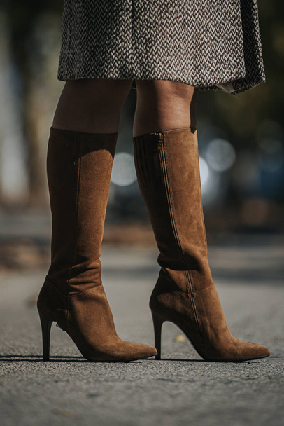 A vertical shot of woman wearing fashionable brown suede knee-high boots outdoors - Foto, imagen