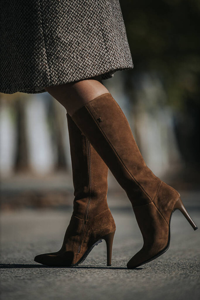 A vertical shot of woman wearing fashionable brown suede knee-high boots outdoors - Фото, изображение