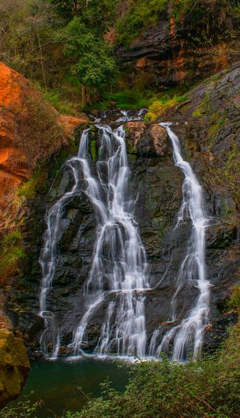 A vertical shot of a waterfall and bright foliage in autumn color - Photo, Image