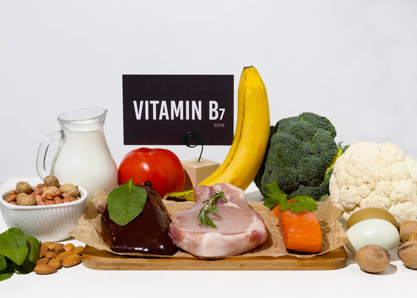 Joukko luonnontuotteita, joissa on runsaasti B7-vitamiinia biotiini. Terveellistä ruokaa. Pahvimerkki, johon on kaiverrettu. Valkoinen tausta. - Valokuva, kuva