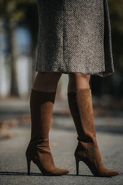 A vertical shot of woman wearing fashionable brown suede knee-high boots outdoors - Fotoğraf, Görsel