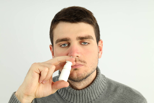Jeune homme avec pulvérisation nasale sur fond clair, concept nez qui coule - Photo, image