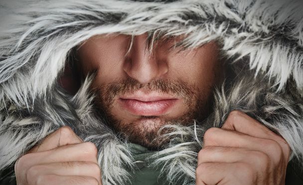 Brutal face of a man with beard bristles and hooded winter - Photo, Image