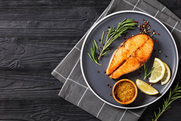 delicious baked salmon steak with wholegrain mustard, lemon, rosemary on a plate, horizontal view from above, flat lay, free space - Zdjęcie, obraz