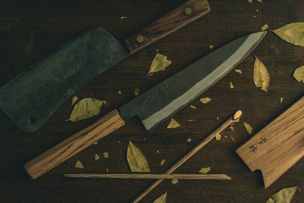 A top view of two sharp knives and pieces of wood on a brown table - Foto, afbeelding