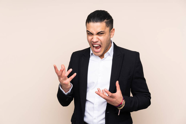 Asian business man isolated on beige background unhappy and frustrated with something - Foto, immagini