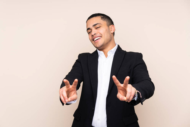 Asian business man isolated on beige background smiling and showing victory sign - Photo, Image
