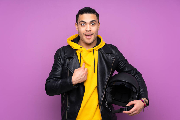 Man with a motorcycle helmet isolated on purple background with surprise facial expression - Фото, изображение