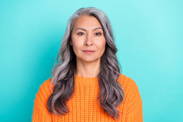Portrait of attractive content calm grey-haired woman wearing orange pullover isolated over bright teal turquoise color background. - Photo, image