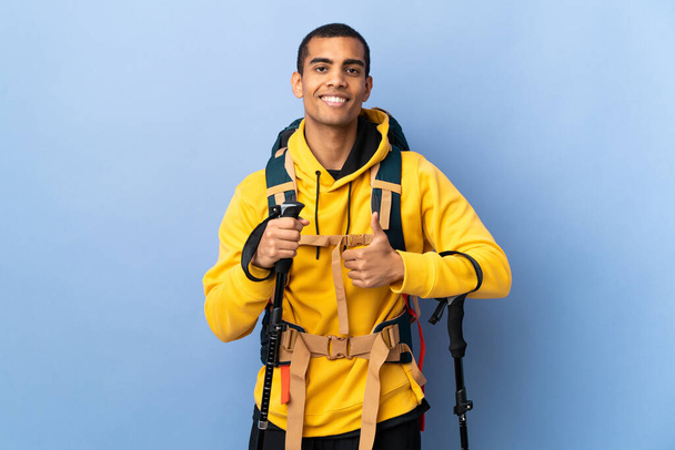 homem afro-americano com mochila e postes de trekking sobre fundo isolado dando um gesto polegares para cima - Foto, Imagem