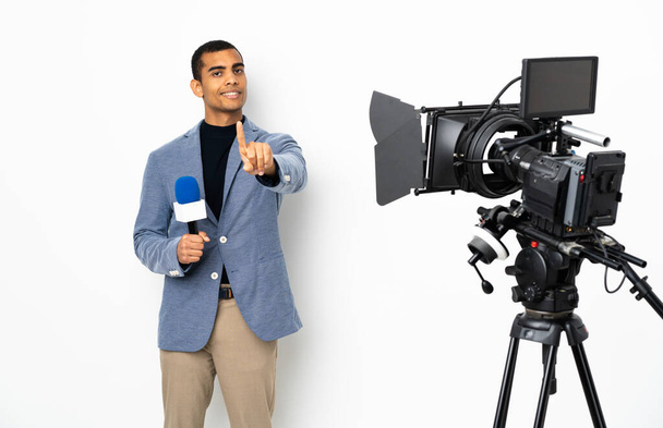 Репортер афроамериканец держит микрофон и сообщает новости на изолированном белом фоне, показывая и пошевеля пальцем - Фото, изображение