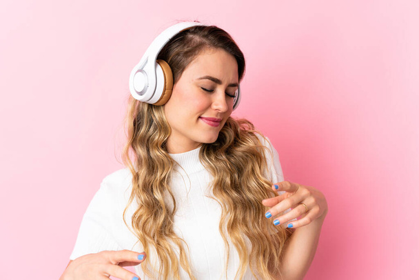 Young brazilian woman isolated on pink background listening music and dancing - Foto, afbeelding