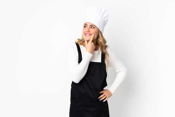 Jonge Braziliaanse chef-kok vrouw geïsoleerd op witte achtergrond denken een idee terwijl op zoek omhoog - Foto, afbeelding