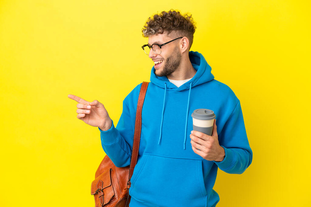 Young student blonde man isolated on yellow background pointing finger to the side and presenting a product - Foto, immagini