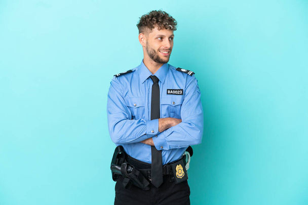 Young police blonde man isolated white on blue background happy and smiling - Zdjęcie, obraz