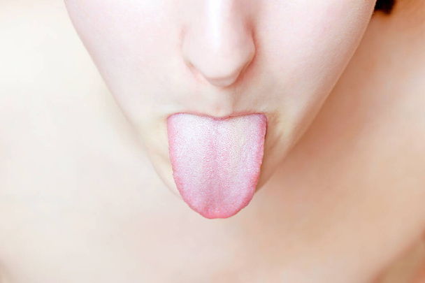 Νεαρή λευκή γυναίκα με ανοιχτό στόμα που δείχνει μια γλώσσα από κοντά. - Φωτογραφία, εικόνα