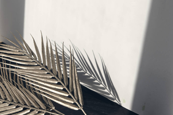 Glanzende tropische palmblad schaduwen op witte grijze keramische beton muur. Abstract pastelachtergrond met kopieerruimte. Platte legglitter confetti. - Foto, afbeelding