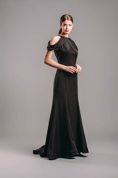 Black evening dress. Studio shot. Beautiful young woman in long sleeveless chiffon dress.  - Фото, изображение
