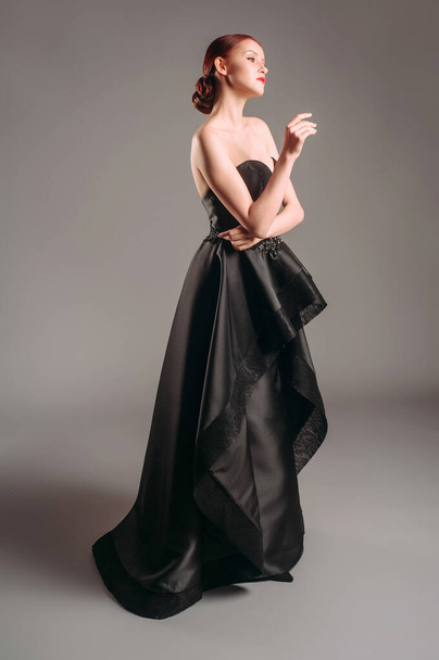 Black evening dress. Attractive young woman in studio. Posh evening gown. A line timeless dress. - Foto, Imagen