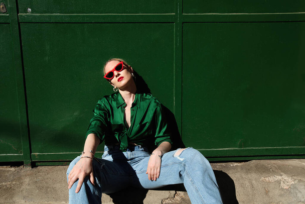 Close-up of young blonde stylish woman, wears sunglasses, posing outdoor. - 写真・画像