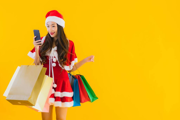 Portrait beautiful young asian woman wear christmas clothes hat with a lot of shopping bag on yellow isolated background - Fotoğraf, Görsel