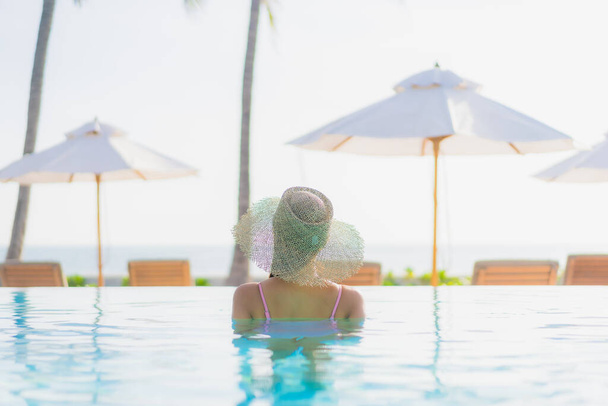 Ritratto bella giovane donna asiatica rilassarsi tempo libero intorno alla piscina all'aperto con vista mare spiaggia oceano in vacanza viaggi - Foto, immagini