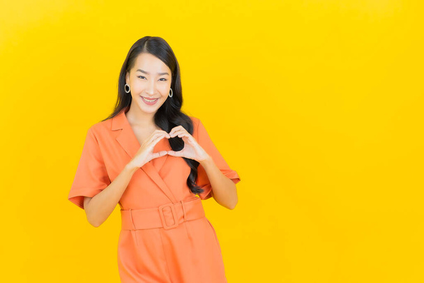 Portret piękny młody azjatycki kobieta uśmiech z akcja na żółty kolor tło - Zdjęcie, obraz